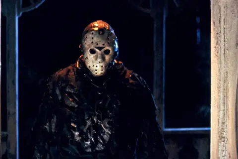 Jason Voorhees, ikonen från fredagen den 13:e filmserie-filmer, står i mörkret med sin ikoniska hockeymask.
