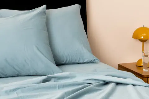 Soft, light blue sheets and pillows create a cozy bed. This material looks like the best material for sheets, promising comfort and style.