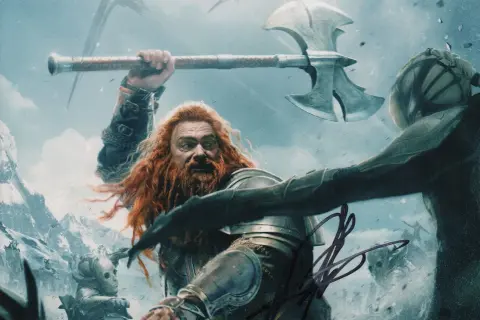Ray Stevenson som en stridande dvärg med rött skägg och en yxa, redo att slåss mot en fiende i en snöig miljö.