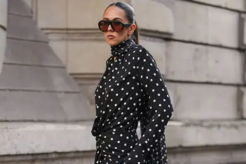 Donna con vestito a pois nero e bianco, occhiali da sole oversize. Come abbinare scarpe a questo look?