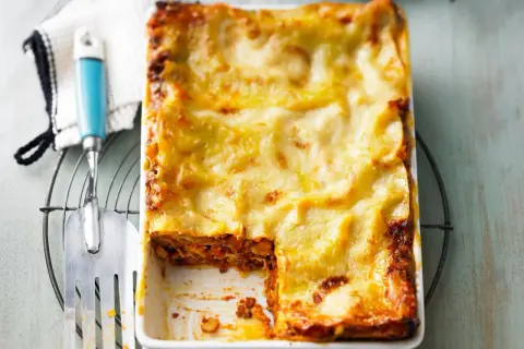 Ein frisch gebackenes, goldbraunes Lasagne-Rezept, original italienisch, mit einer Portion entnommen.
