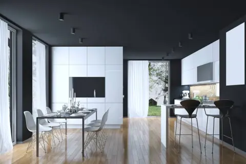 Cucina moderna con mobili bianchi lucidi, soffitto nero e pavimento in legno. Un tavolo da pranzo con sedie bianche e un'isola con sgabelli neri. Perfetti colori da abbinare al bianco e nero.