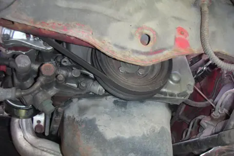Detaljer från motorutrymmet, redo för kamkedja byte. Remmar och delar syns tydligt.
