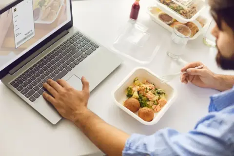 Praca przy laptopie i posiłek z cateringu. Zastanawiasz się nad usługą cateringową a odliczeniem VAT?