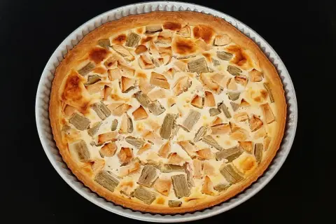 Tarte rhubarbe pomme dorée, garnie de morceaux de fruits et d'une crème onctueuse, prête à être dégustée.