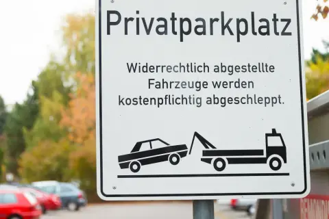 Schild "Privatparkplatz": Widerrechtlich abgestellte Fahrzeuge werden kostenpflichtig abgeschleppt. Wer zahlt den Abschleppdienst? Der Falschparker!