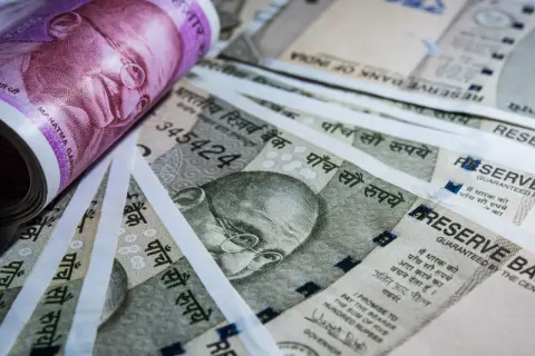 Stos banknotów, w tym fioletowy 2000 rupii i szare 500 rupii, z wizerunkiem Mahatmy Gandhiego. Waluta Indii.