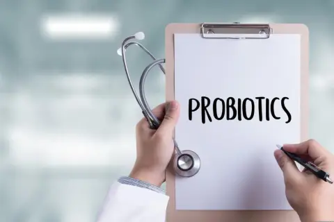 Lekarz trzyma stetoskop i notatnik z napisem "PROBIOTICS". Zastanawia się, do kiedy podawać probiotyk niemowlakowi.