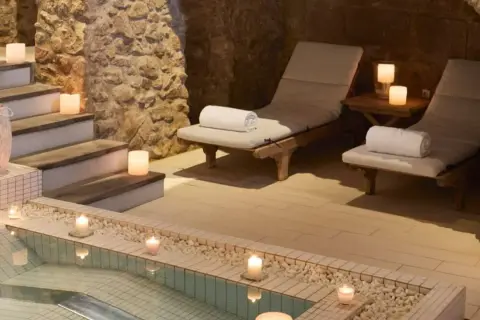 Relájate en este spa urbano con piscina, tumbonas y velas. Un oasis de paz y tranquilidad.