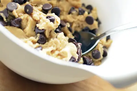 En skål med chokladkakdeg, redo för ett cookie dough recept. En sked sticker upp ur den ljuvliga smeten.