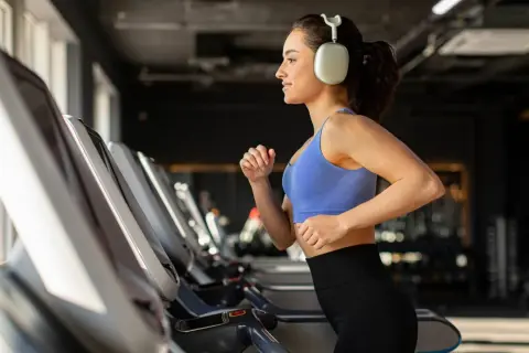Junge Frau läuft auf Laufband im Fitnessstudio, motiviert für Fitness und Abnehmen.