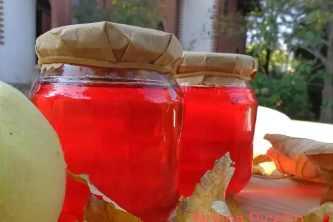 Due barattoli di gelatina di mele cotogne, con mele e foglie autunnali.