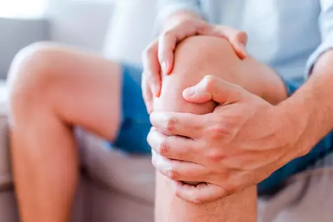Mann hält sein Knie, das einen stechenden Schmerz im Knie anzeigt.