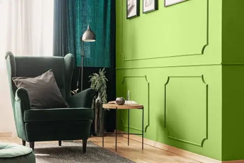 Zielona, aksamitna sofa i zasłony tworzą przytulną atmosferę. Kolor oliwkowy z jakim kolorem pasuje? Zobacz, jak świetnie komponuje się z jaskrawą zielenią ścian.