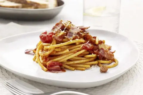 En portion pasta amatriciana med tomatsås, bacon och parmesanost.