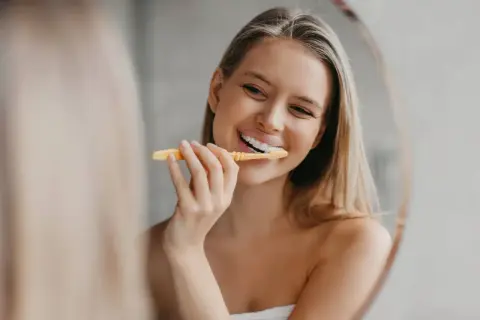 Uśmiechnięta blondynka myje zęby. Pytanie brzmi: ile razy dziennie myć zęby, by mieć taki promienny uśmiech?