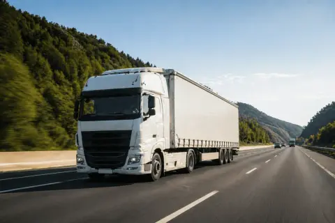 Un camion blanc roule sur une autoroute bordée d'arbres. Le conducteur utilise un chronotachygraphe numérique pour enregistrer son trajet.