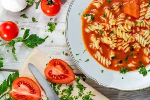 Aksamitna pomidorowa z rosołu z makaronem fusilli, świeżymi pomidorami i natką pietruszki.