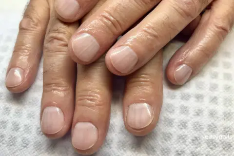 Dłonie z zadbanymi paznokciami po zabiegu manicure męski. Paznokcie są czyste, wypielęgnowane i lekko nabłyszczone.