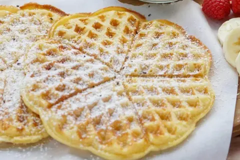 Zarte Buttermilch Waffeln, bestäubt mit Puderzucker, warten auf ein leckeres Frühstück.