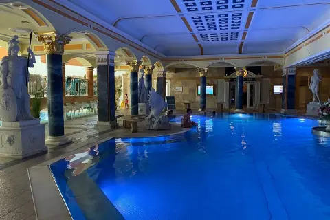 Prunkvoller Innenpool mit blauer Beleuchtung, antiken Statuen und Säulen. Ein Ort der Entspannung in den Teplice Therme.