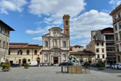 Piazza Ognissanti con la facciata della chiesa di San Salvatore in Ognissanti, una scultura al centro e palazzi circostanti.