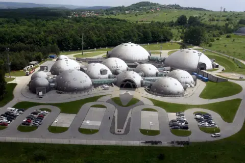 Kompleks kopuł przypominający bazę na planecie Alvernia, otoczony zielenią i lasem.
