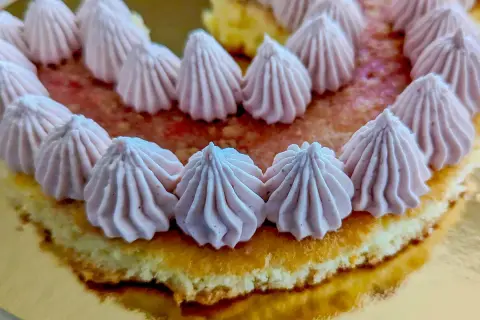Gâteau orné de rosaces de ganache chocolat blanc framboise sur un lit de fruits rouges.
