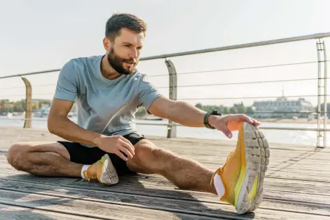 Mann dehnt sich am Wasser. Er fragt sich, wie lange Dehnung halten für optimale Ergebnisse.
