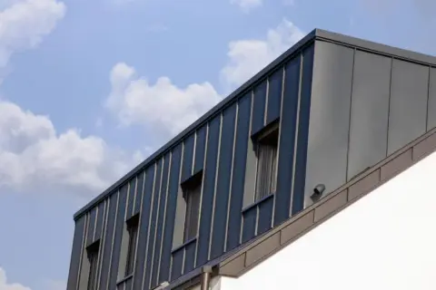 Moderne Dachgaube mit stehenden Blechbahnen und Fenstern. Informieren Sie sich über Dachgaube Kosten für Ihr Bauprojekt.