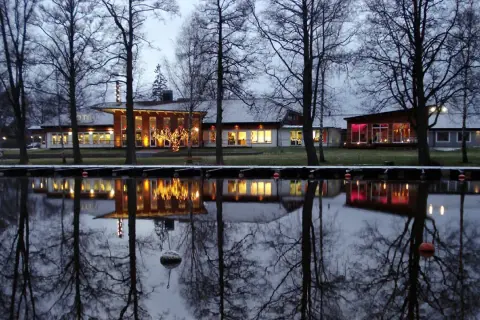 Vinterkväll vid Best Western Norra Vättern. Hotellets ljus speglas i vattnet, omgivet av kala träd.