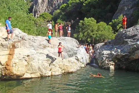 Gente salta a un río en la **Benahavís ruta río**. Un día soleado para disfrutar de la naturaleza y el agua.