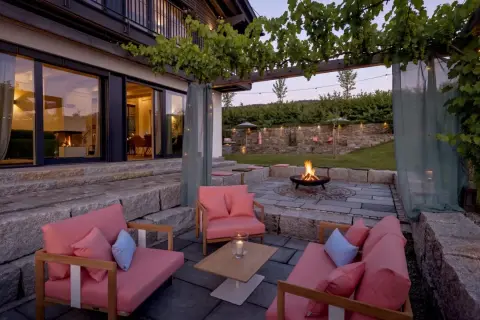 Gemütliche Lounge-Möbel und ein Feuerkorb laden zum Entspannen ein. Die Weinreben über der Pergola und Lichterketten schaffen eine romantische Atmosphäre, perfekt, um die Terrasse zu dekorieren.