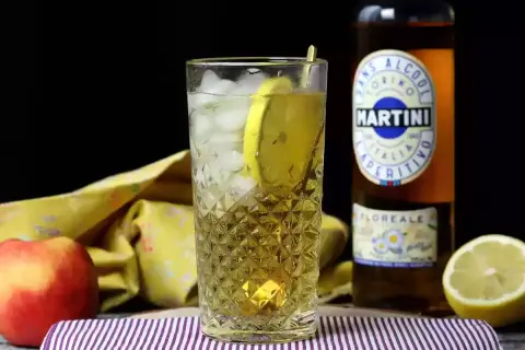 Orzeźwiający Martini Floreale z lodem i cytryną, obok jabłka i butelki Martini.