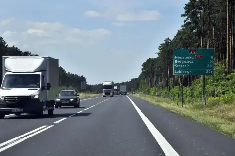 Droga ekspresowa jednojezdniowa S10 wśród lasu. Samochody i ciężarówki jadą w kierunku Nieszawki, Bydgoszczy, Szczecina i Lubieszyna.
