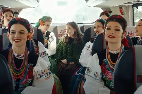 Uśmiechnięte dziewczyny w strojach ludowych, podróżujące autobusem Mazda. Kolorowe korale i haftowane bluzki.