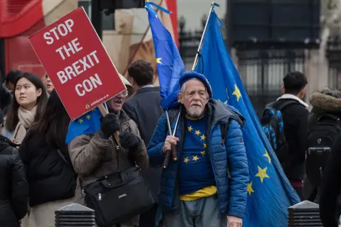 Protestujący w Wielkiej Brytanii z flagami UE i transparentem "Stop the Brexit Con".