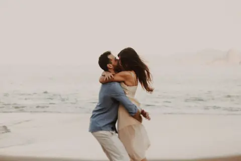 Pareja besándose en la playa, un abrazo que expresa los lenguajes del amor.