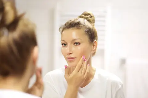 Donna si applica un siero sul viso, chiedendosi quanti sieri si possono usare insieme per una pelle luminosa.
