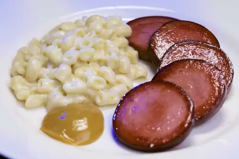 En tallrik med stuvade makaroner, skivad falukorv och en klick senap. En snabb och klassisk svensk måltid.