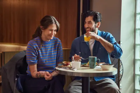 Ett leende par njuter av en god frukost på Scandic Örebro. Mannen dricker apelsinjuice medan kvinnan ler åt honom.