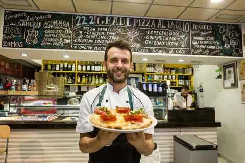 Chef sonriente en Zaragoza ofrece una pizza artesana. ¡Los soletes Repsol de esta pizzería son deliciosos!