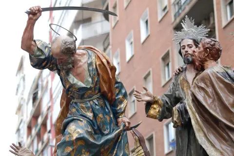 Escena de la **procesión Domingo de Ramos**: un hombre con túnica dorada levanta un sable, mientras otro hombre besa a Jesús.
