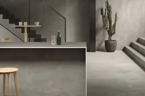 Un intérieur moderne avec un escalier, un bar et un cactus. Le sol et les murs sont recouverts d'un élégant carrelage sans joint.
