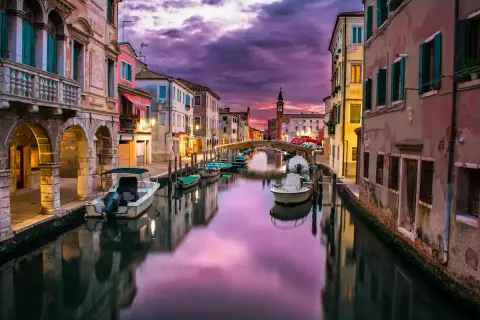 Un canal vénitien au crépuscule, avec des bateaux et des bâtiments colorés. Le ciel violet et rose, reflet de l'eau, illustre parfaitement ce qu'est le HDR.