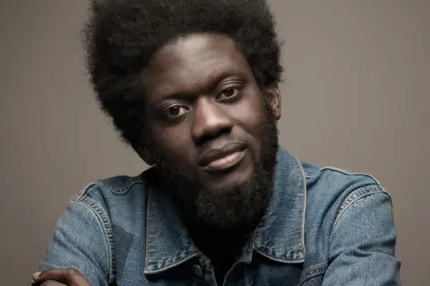 Michael Kiwanuka w dżinsowej kurtce, gotowy na koncert.