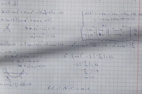 Ręcznie pisane równania matematyczne i wykres paraboli na kratkowanym papierze.