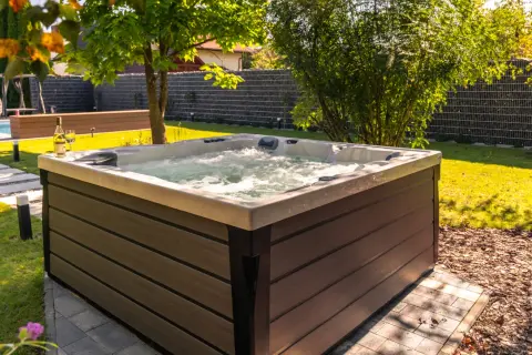 Relaks w ogrodzie przy bąbelkach jacuzzi. W tle widać basen i huśtawkę.