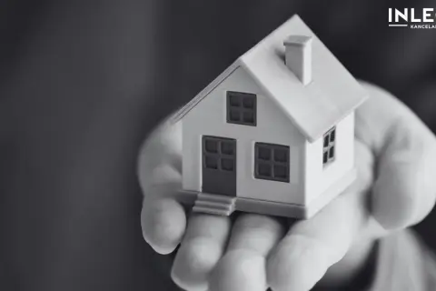 Miniatura domu na dłoni, symbolizująca ograniczone prawa rzeczowe i bezpieczeństwo posiadania.