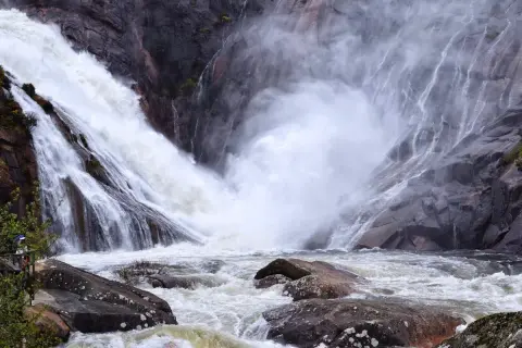 La cascada más grande de Galicia, Ézaro, desciende con fuerza por rocas grises, creando una nube de vapor sobre el río caudaloso.
